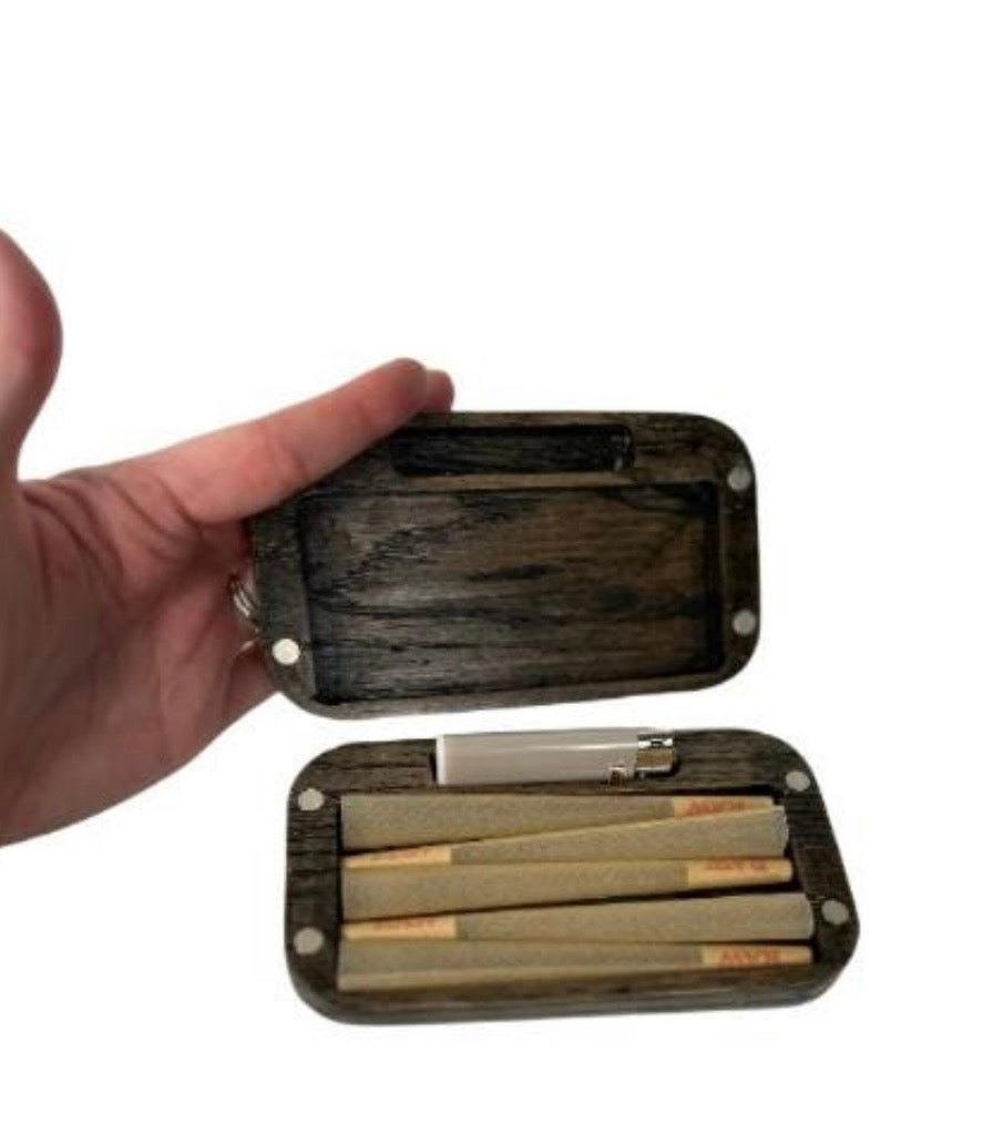 Hand holding an open wooden case with rolled papers and a lighter on a white background