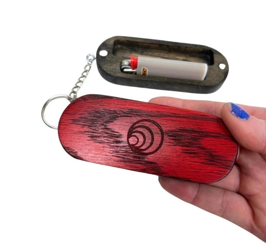 Red wooden lighter case with keychain and built-in lighter held by a hand.