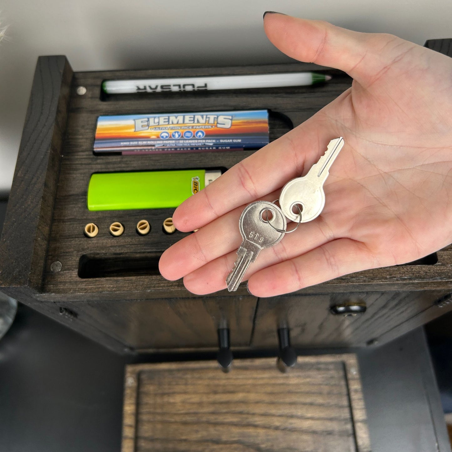 Hand holding keys above a lockable stash box storage box