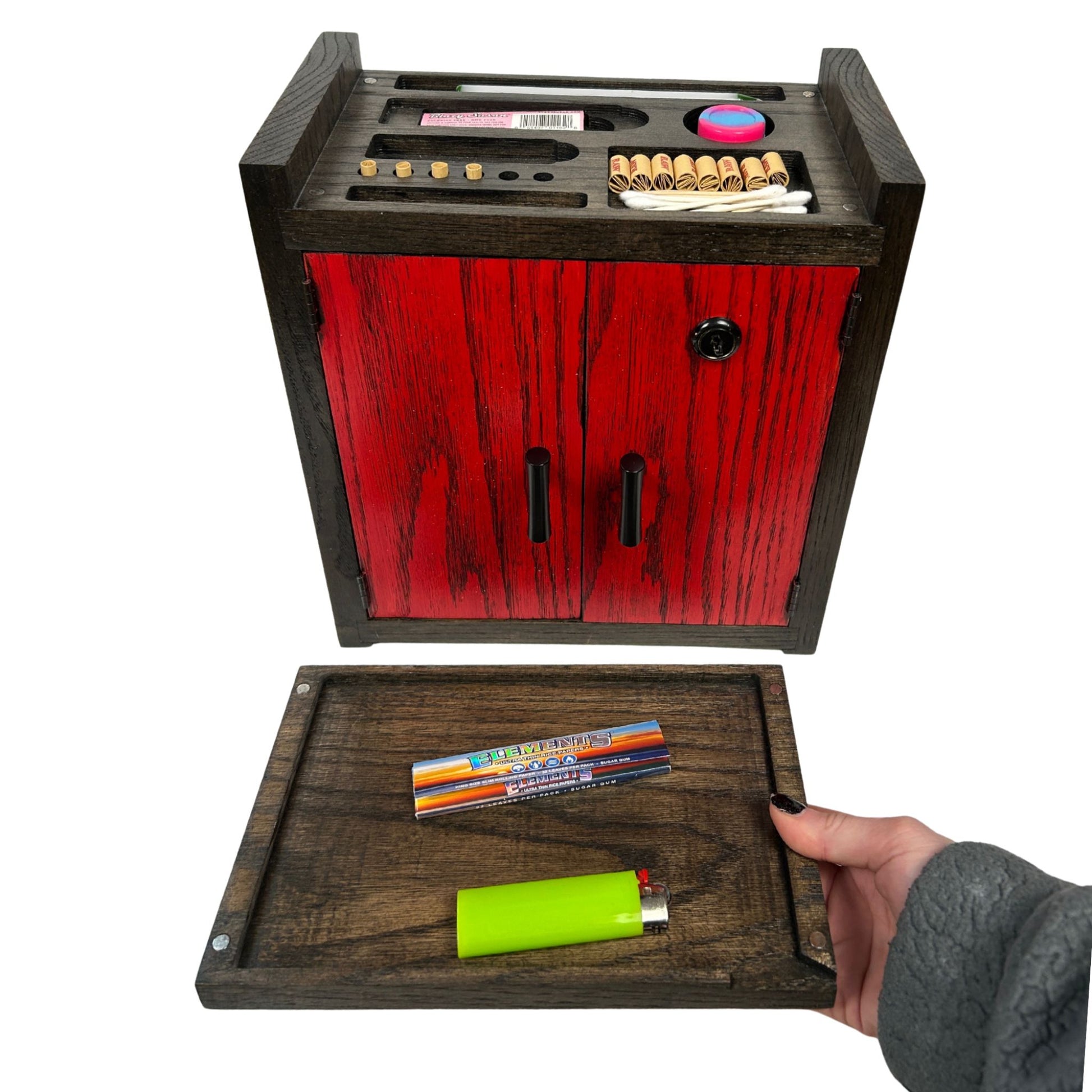 Red wooden stash box with compartments, including a hand holding a lighter and accessories.
