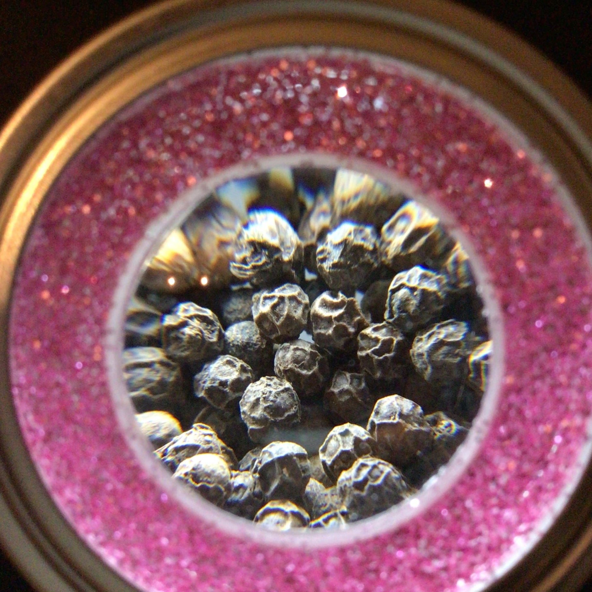 magnified spice jars in spice rack. close up of peppercorn through mag jar