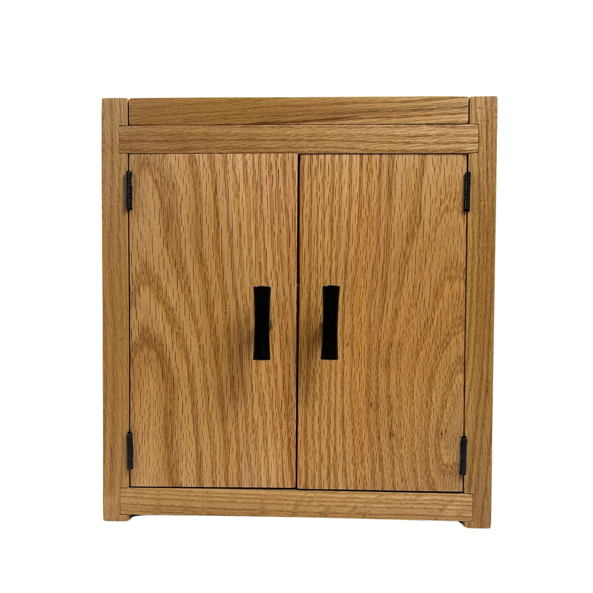 A small wooden cabinet with two doors, featuring a warm medium-brown wood grain finish and contrasting black metal handles, shown against a plain white background.